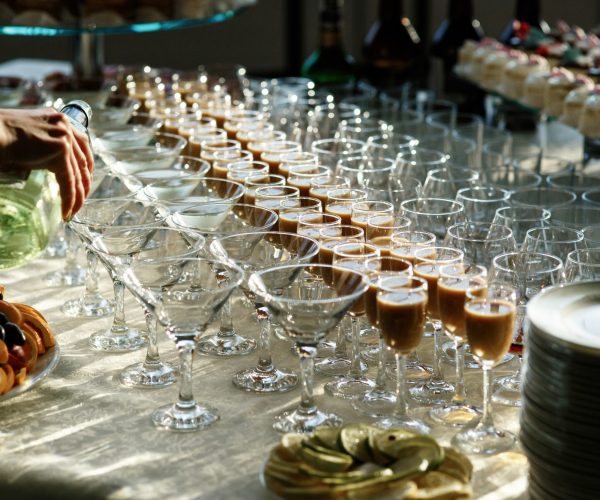 Man pours martini in cocktail glasses on dinner table