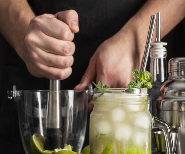 person-making-cocktails-with-alcohol-lime